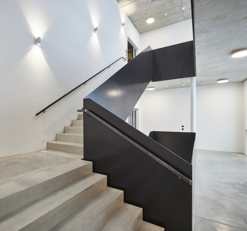 Beleuchtestes Treppenhaus der Kanzlei mit Betonstufen im Industrie-Design.